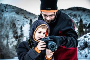 Father shows son how to operate a DSLR camera outdoors