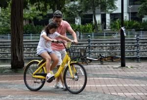 A man helps a girl on a bike