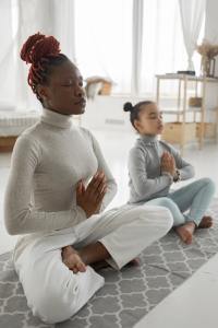 Woman and girl doing yoga meditation together