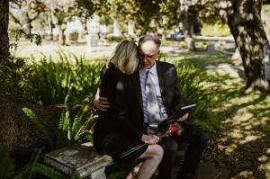 A man comforts a grieving woman at a cemetery