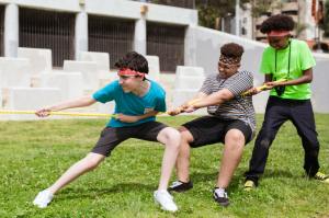 Three diverse teens pull on a rope together