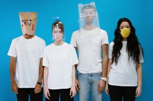 Four people wearing a variety of silly masks