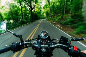 POV rider on a motorcycle ride on forested road