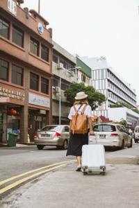 Young woman walks away with suitcase on city street