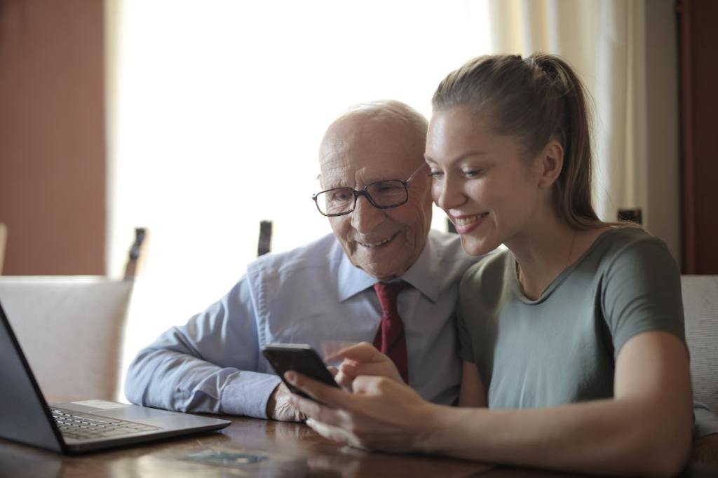 A young woman shows her phone to her grandfather