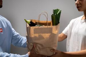 Store manager hands bag of groceries to woman