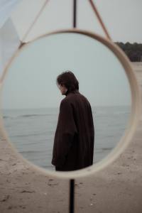 Person reflected in mirror standing on a beach