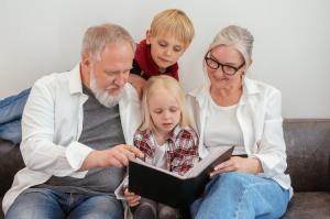 Two grandparents look at photo album with children