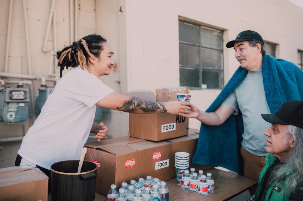 A volunteer hands a cup to a person in need