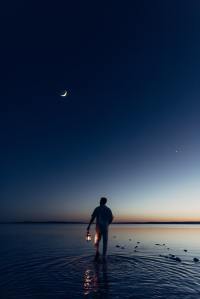 Man walks on beach with lantern